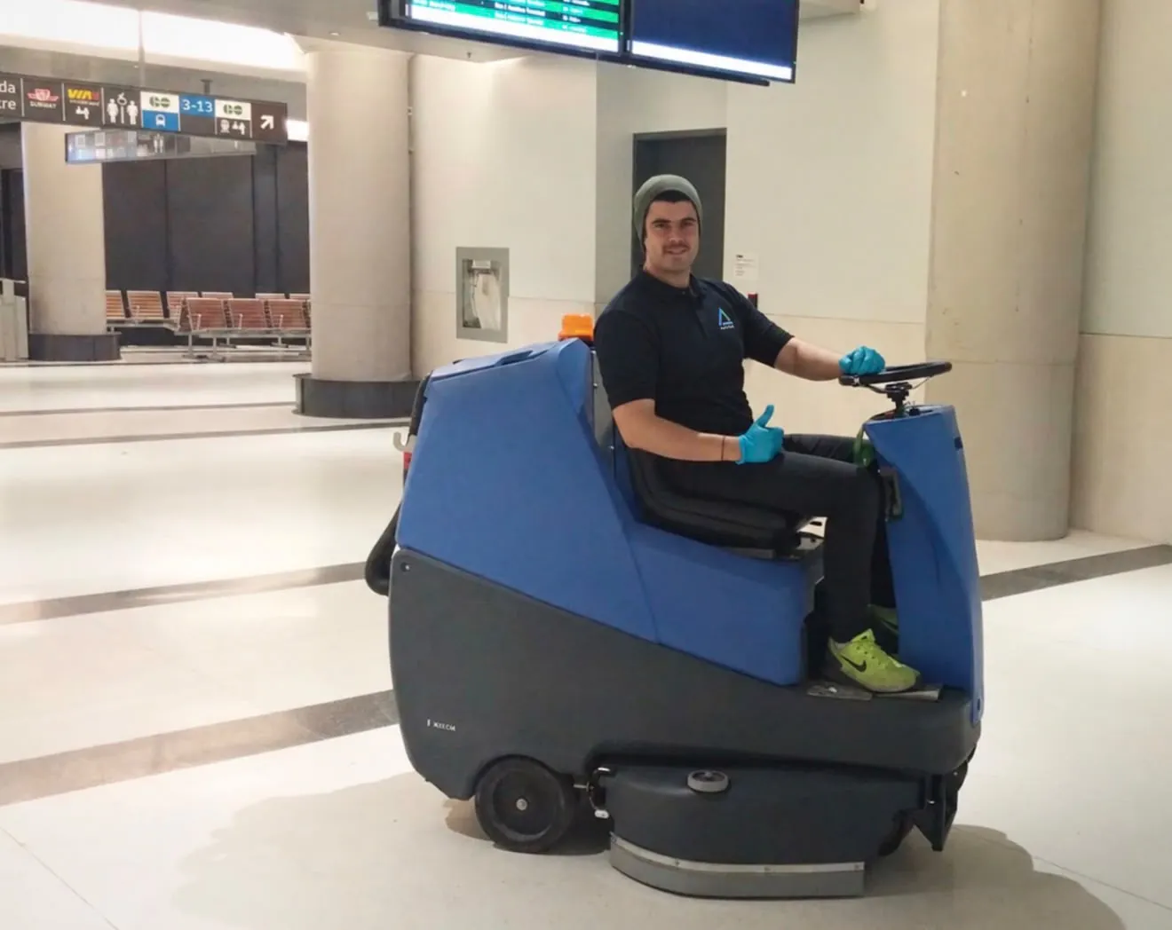 A ride-on floor scrubber cleaning a large public hall